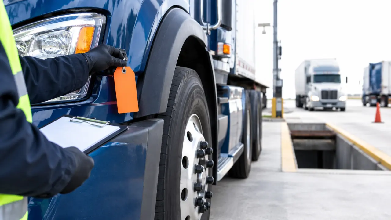 Roadside inspector placing an out-of-service tag near a truck's wheel